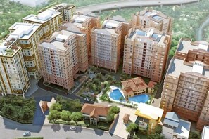 A high-rise residential building complex with multiple apartment buildings, a swimming pool, and a small park area.