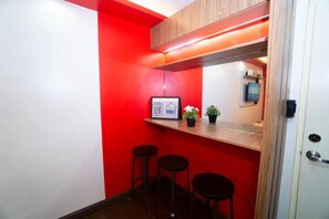 A small kitchenette with a red wall, a wooden countertop, and two black stools. - Near Manila Airport. Lovely "HOTEL STYLE" Studio Condo, With Kitchenette + Swimming Pool, 7A (Paranaque)