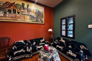 A room with a traditional sofa set, a small table with a floral tablecloth, and a painting on the wall. - Lao Hmong Hotel（Luang Prabang Old Town Center Store near JC Supermarket) (Luang Prabang)