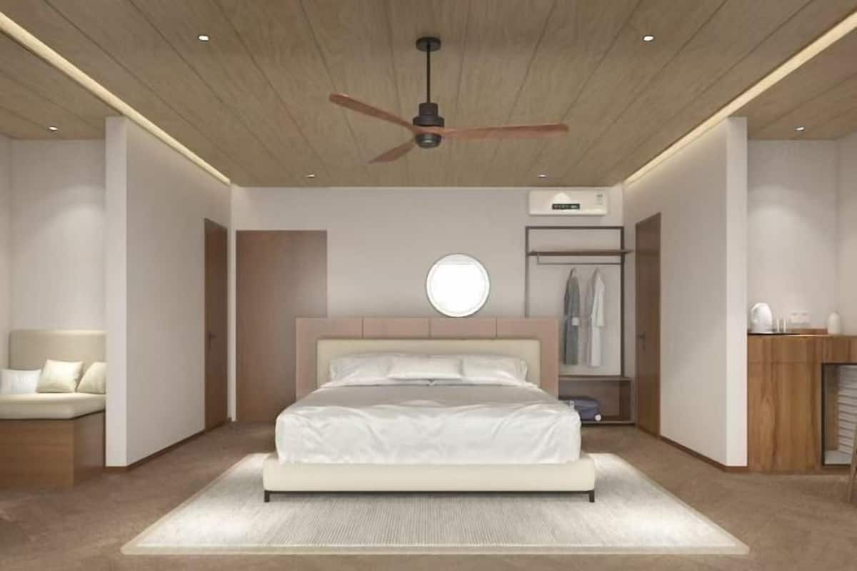 A modern bedroom with a bed, a ceiling fan, a round mirror, a wardrobe, and a bedside table.