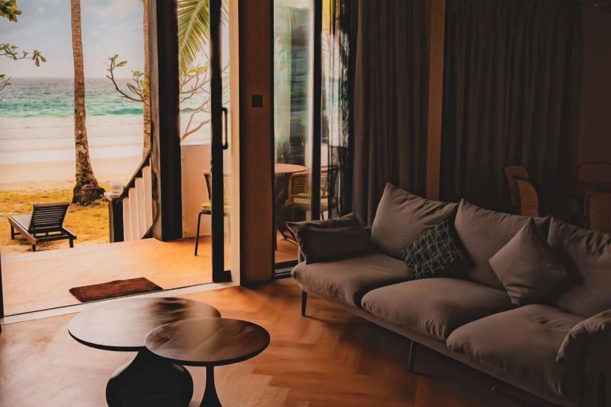 A modern living room with a sofa, a coffee table, and a view of the beach.