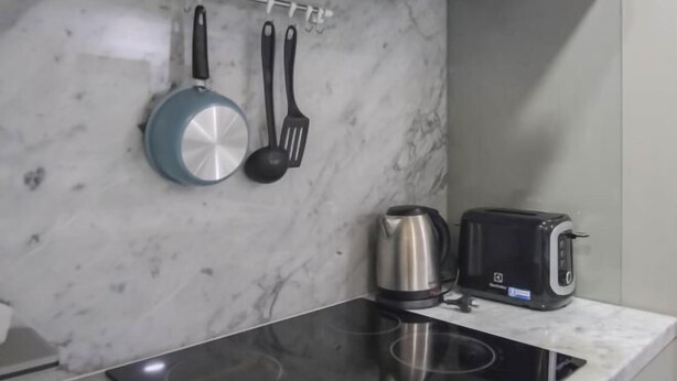 A kitchen with a marble backsplash, a kettle, a toaster, and utensils hanging on the wall. - Roxpresso Nimman 15 (Chiang Mai)