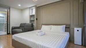 A hotel room with a large bed, a seating area, and a compact air purifier. - Roxpresso Nimman 15 (Chiang Mai)