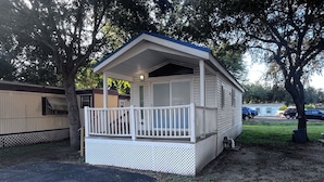 A mobile home with a porch and a fenced yard. - The Shady Oaks, with Pool Access! (Harlingen)