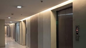A hallway with a modern elevator, a clean floor, and a wall-mounted control panel. - Thompson Suites High Street (Fort Victoria) (Taguig)