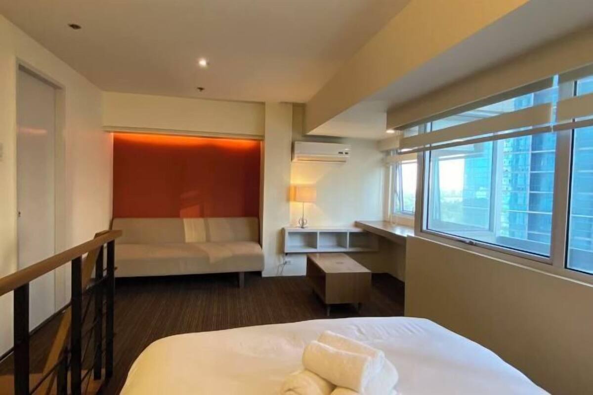 A hotel room with a bed, a sofa, a desk, and a window.