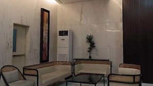 A modern lobby with marble walls, a large air conditioning unit, and wicker furniture. - Thompson Suites High Street (Fort Victoria) (Taguig)