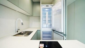 A compact kitchen with a built-in sink, a refrigerator, and a narrow countertop. - Busan Ocean Stay (Busan)
