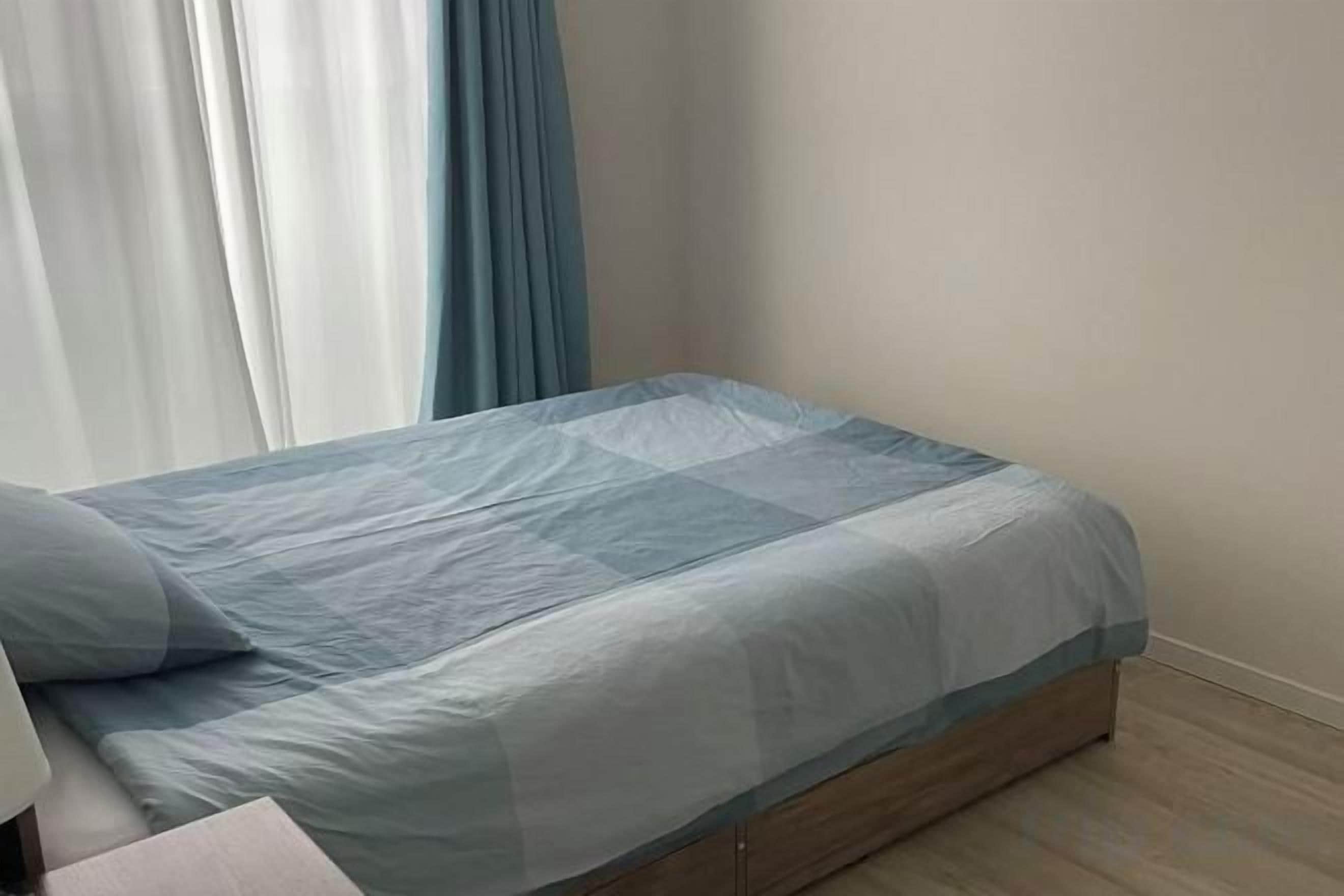 Een bed met een blauw beddegoed en een houten hoofdeinde.