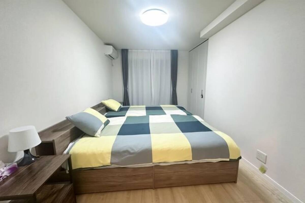 Une chambre à coucher avec un lit en bois, une table de chevet avec une lampe et une fenêtre avec des rideaux.