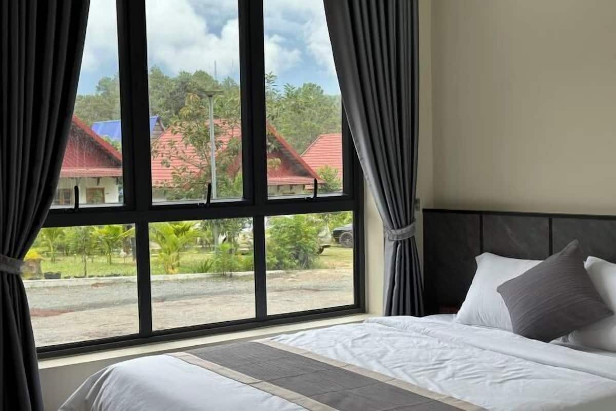 A bedroom with a large window, a bed, and curtains.