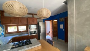 A kitchen with wooden cabinets, a granite countertop, a gas stove, and two woven pendant lights. - House with the best view of Barra Grande Piauí (Cajueiro da Praia)