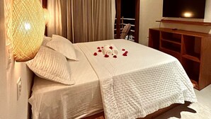 Ein ordentlich bezogenes Bett mit weißer Bettdecke, einer Nachttischlampe und einem digitalen Thermostat auf dem Nachttisch.