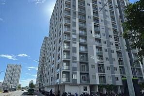 Ein mehrstöckiges Wohngebäude mit Balkonen, blauem Himmel und einer Straße im Vordergrund.