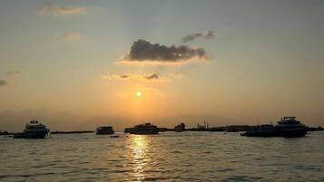 A sunset over a body of water with several boats.