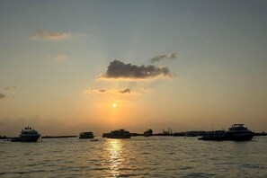 Ein Sonnenuntergang über einem Gewässer mit mehreren Booten.