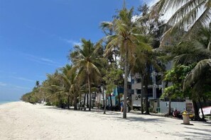 Una playa con palmeras y un edificio de varios pisos.