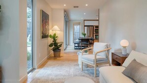 A modern living room with a sofa, armchair, and a dining area in the background. - Modern Austin Home w/ Pool, Putting Green & Coffee Nook Townes Retreat by Avantstay (Austin)