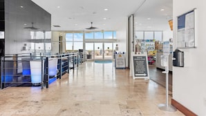 A spacious indoor area with a clear view of the outside through large windows, a ceiling fan, and a signboard with information. - Beachfront Stay w/ Resort Amenities & Gulf Views Sterling Breezing #506 (Panama City Beach)