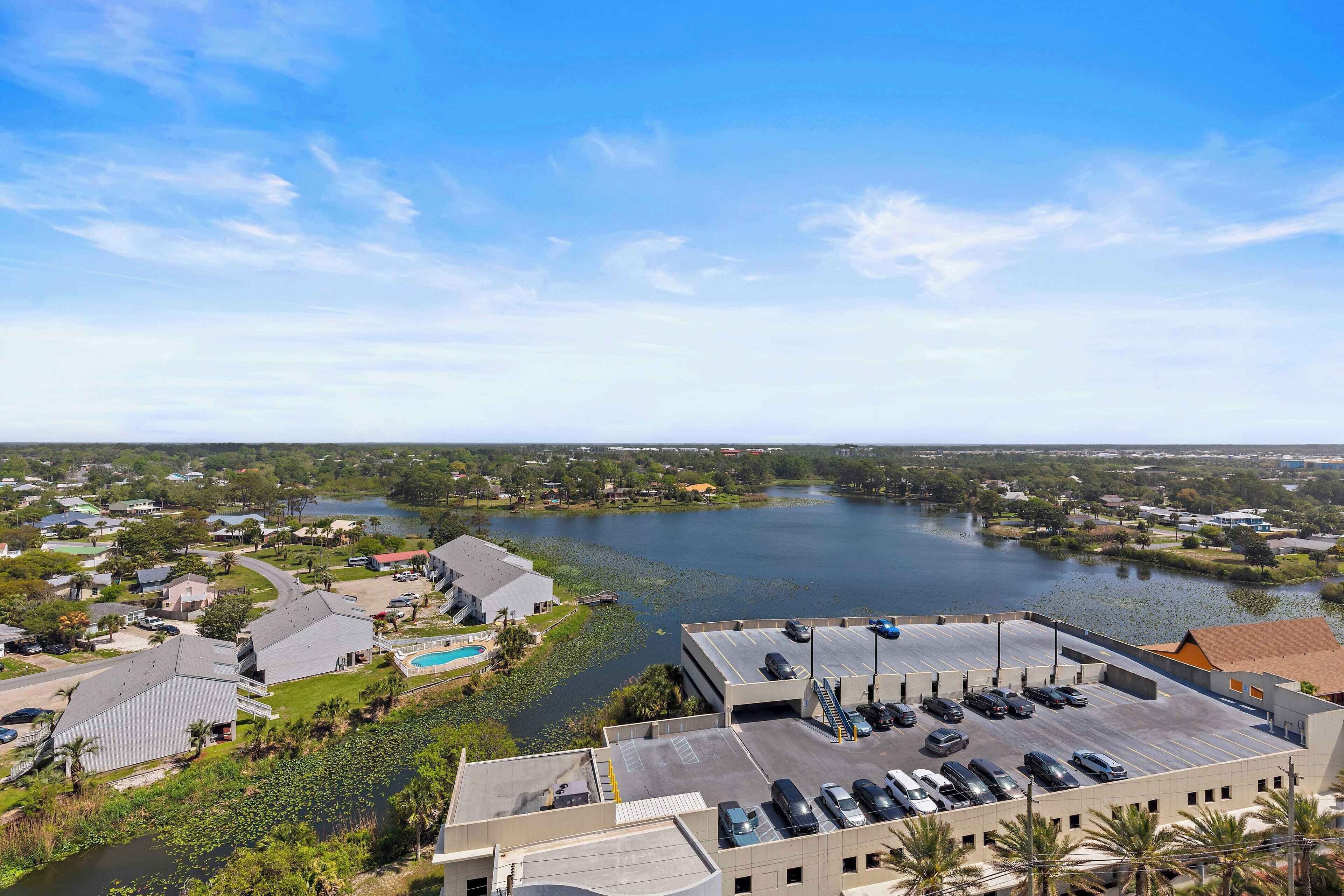 A view of a waterfront property with a parking lot, buildings, and a lake.
