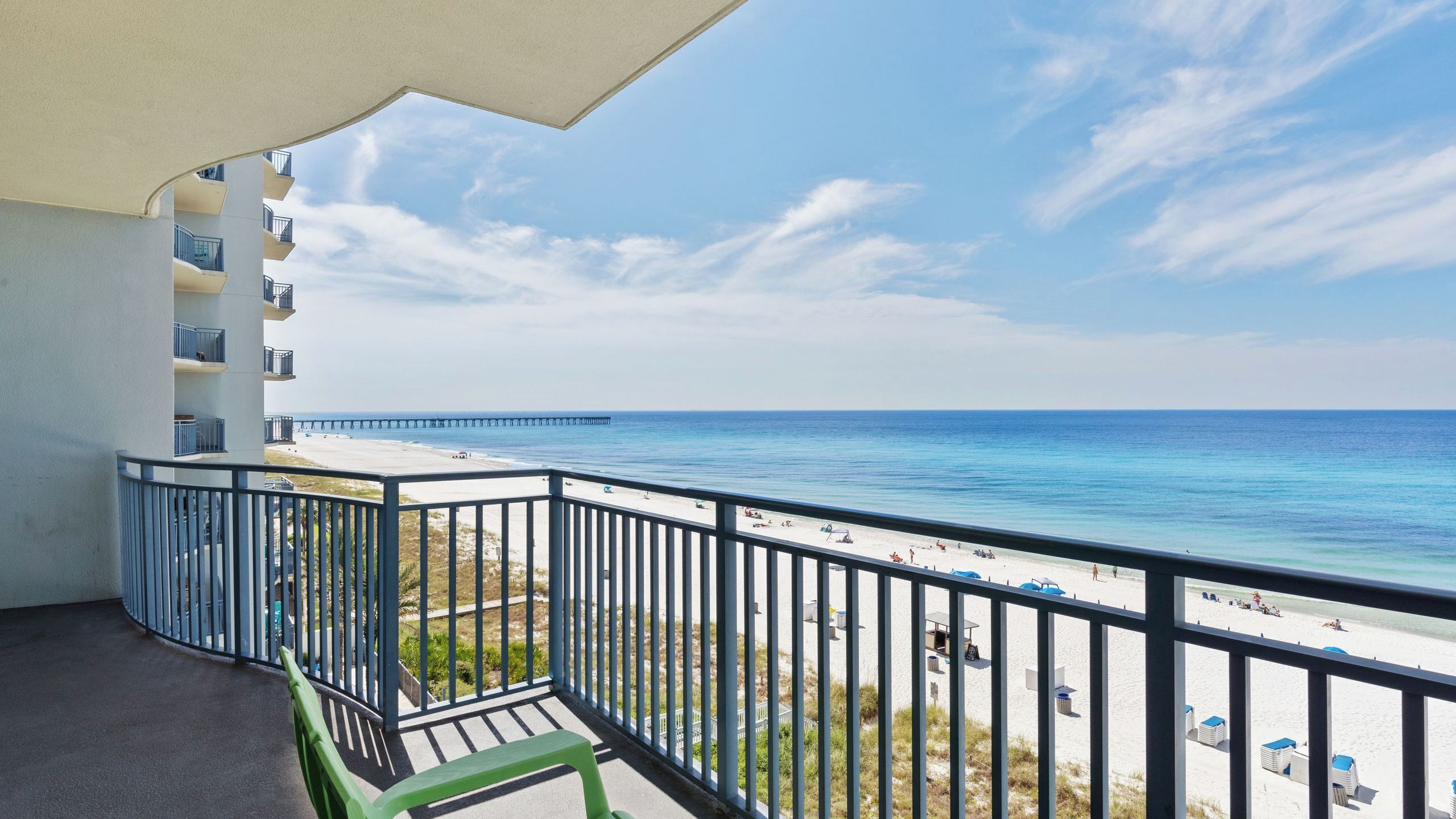 A balcony with a view of the beach and pier.