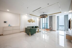 A modern living room with a sofa, a dining table, and a TV. - The Suite Landmark - Vinhomes Central Park (Ho Chi Minh City)