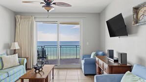 A hotel room with a balcony, a TV, a sofa, a coffee table, and a desk. - Sterling Breeze #604 Beachfront Condo w/ Balcony, Pool, Hot Tub & Pier Park (Panama City Beach)