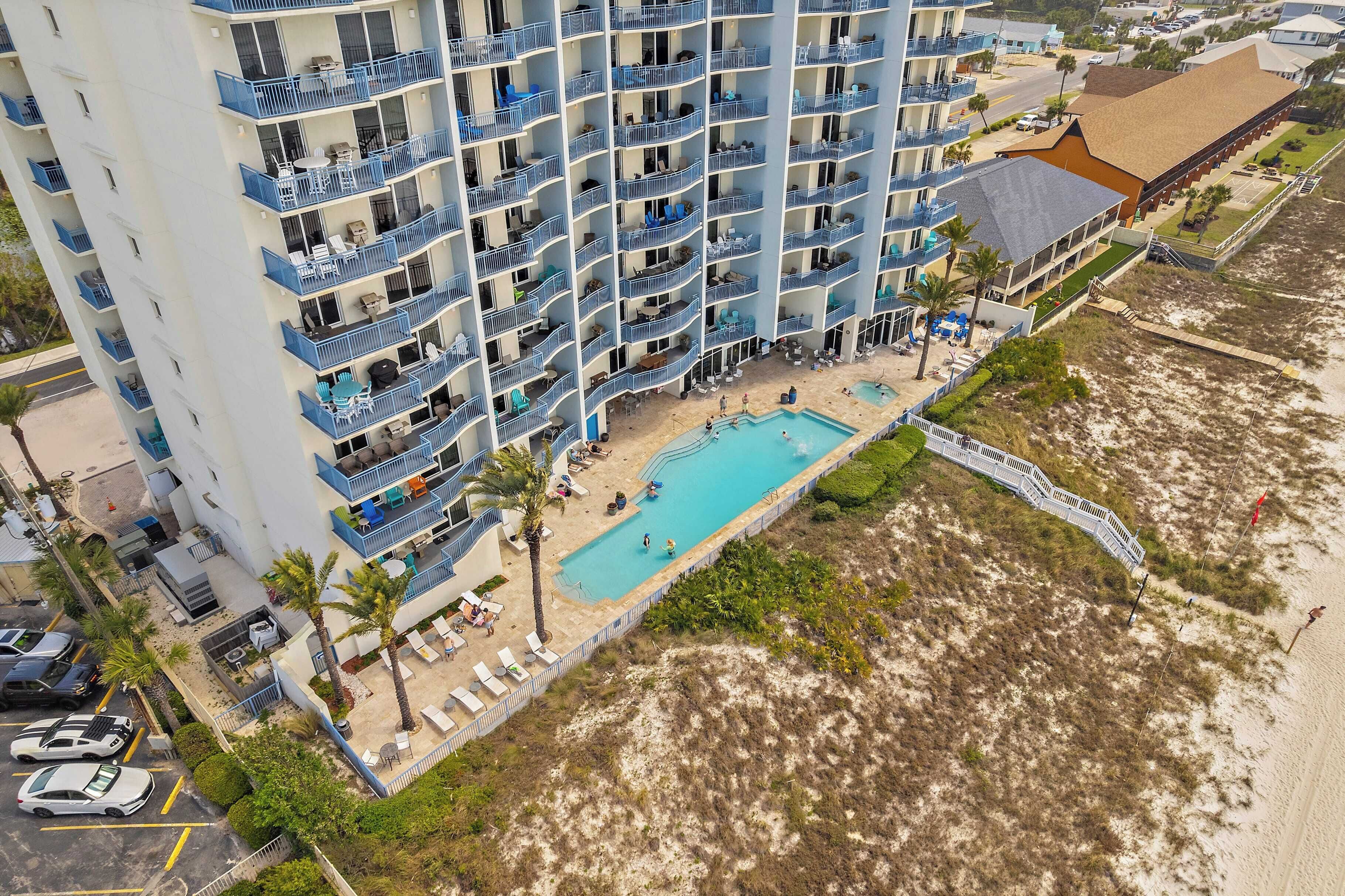 Un hotel de gran altura con varios balcones, una piscina y vistas a la playa.