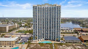 A high-rise hotel with multiple floors, a swimming pool, and a view of a lake. - Sterling Breeze #604 Beachfront Condo w/ Balcony, Pool, Hot Tub & Pier Park (Panama City Beach)