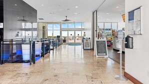 A spacious indoor area with a clear view of the outside through large windows, a ceiling fan, and a signboard with information. - Sterling Breeze #604 Beachfront Condo w/ Balcony, Pool, Hot Tub & Pier Park (Panama City Beach)