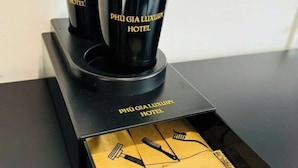 En svart kaffebryggare med logotypen för ”PHU GIA LUXURY HOTEL”, placerad på ett svart bricka med en logotyp i guld.