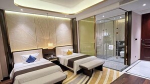 Camera d'albergo con due letti, una panca, zona doccia in vetro e design moderno.