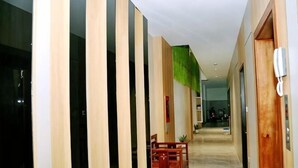 Un pasillo con paneles de madera, un teléfono y una silla.