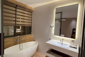 Un baño moderno con una bañera independiente, un tocador con espejo y un perchero para toallas.