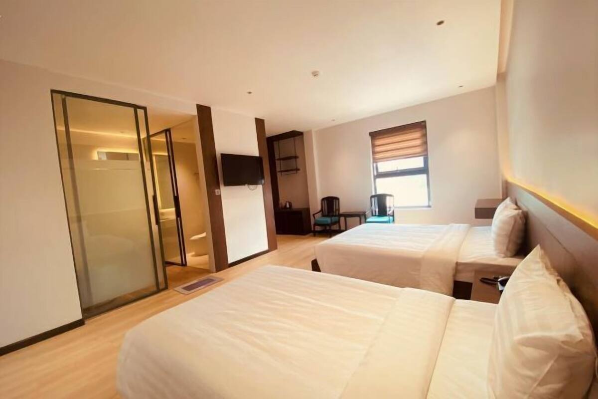 Une chambre d’hôtel avec deux lits, une télévision, un bureau et une porte coulissante.