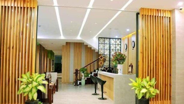Zona de recepción con un mostrador de madera, una escalera y plantas en macetas.