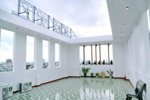 Una terraza amplia en la azotea con ventanas grandes, suelo estampado en tonos verdes y barandilla de metal.