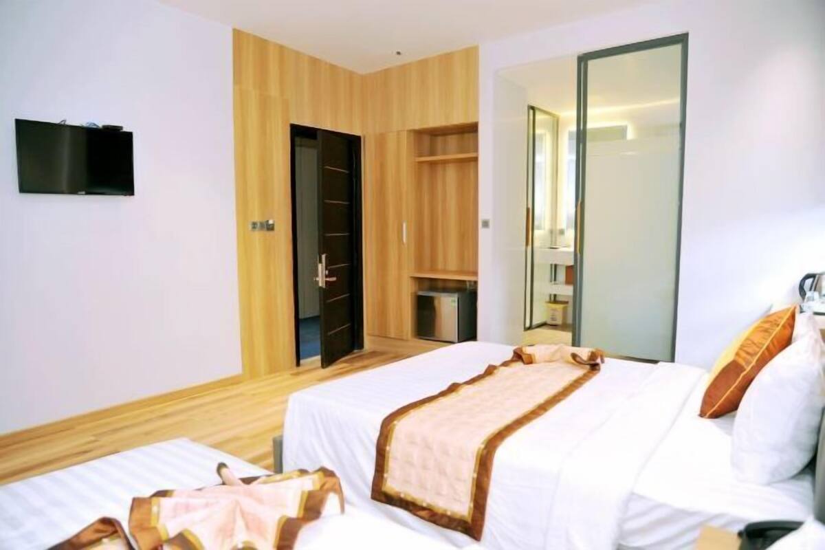 Une chambre d’hôtel avec deux lits, une armoire, une télévision et un miroir.