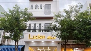 Un hotel llamado Lucien Hotel con una fachada moderna, ventanas amplias y una entrada visible.