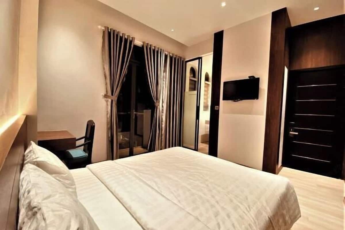 Une chambre d’hôtel avec un lit, une chaise, une télévision et une porte.