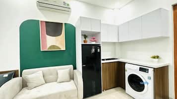 A compact living space with a sofa, kitchenette, and a washing machine.