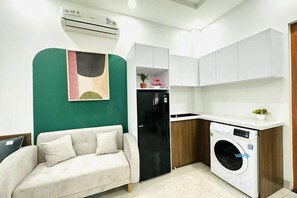 A compact living space with a sofa, kitchenette, and a washing machine.