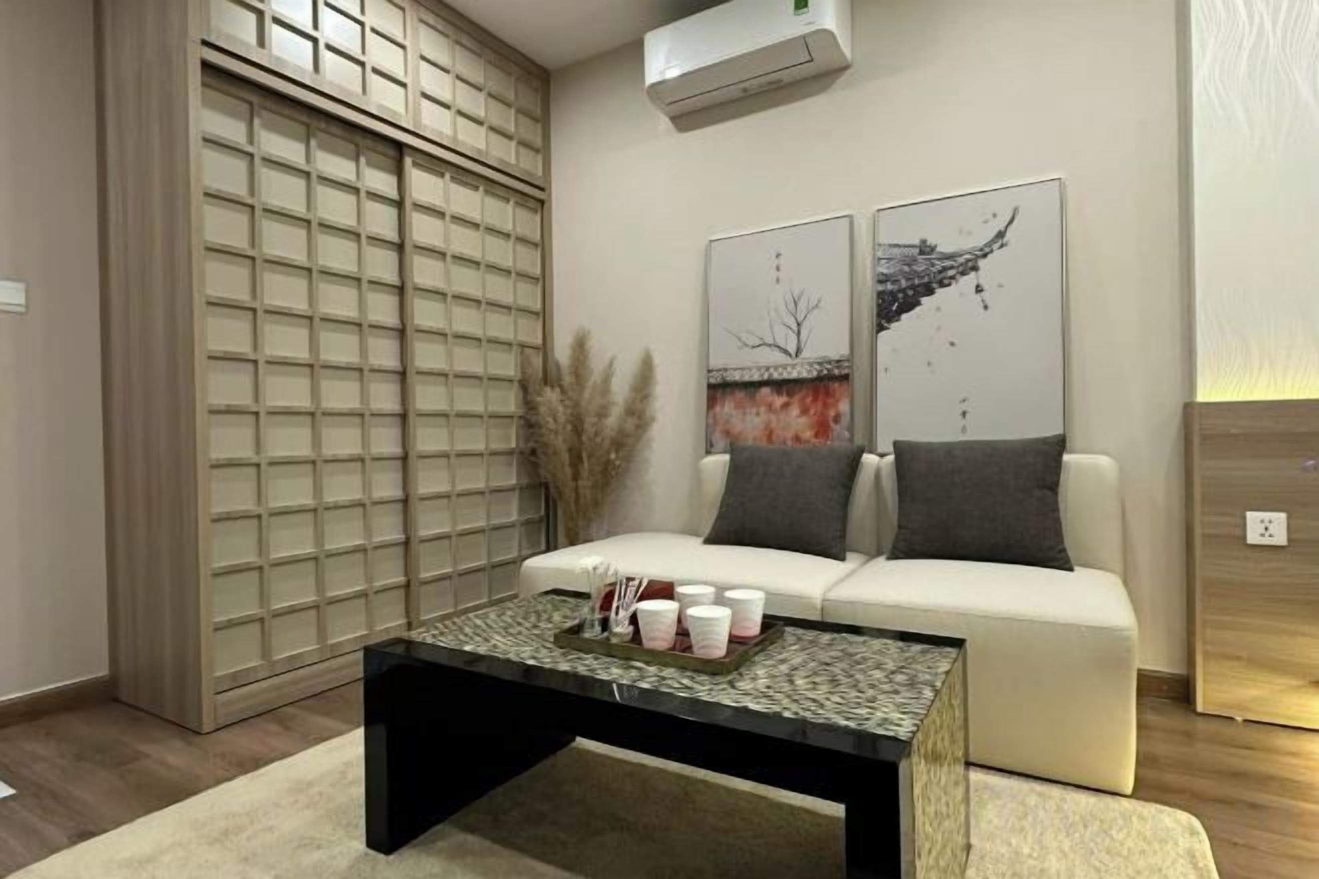 A modern living room with a sofa, a coffee table with decorative items, and artwork on the wall.