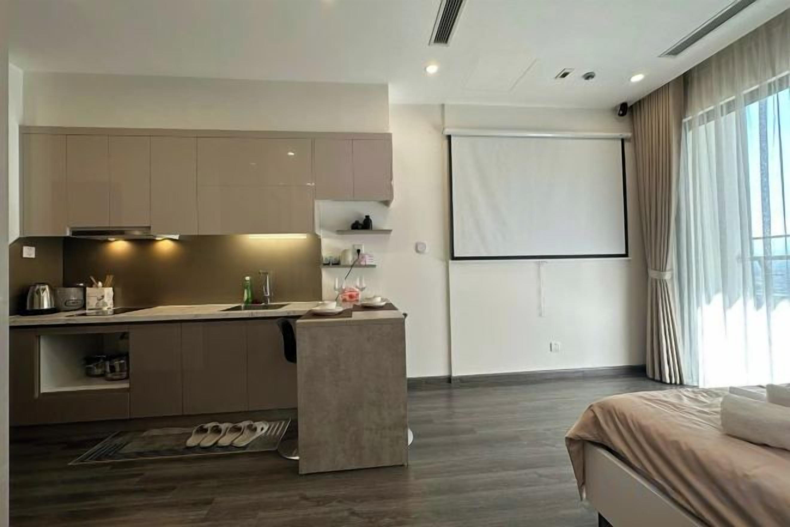 Una habitación de hotel moderna con kitchenette, una cama y un ventanal grande.