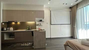 Una habitación de hotel moderna con kitchenette, una cama y un ventanal grande.