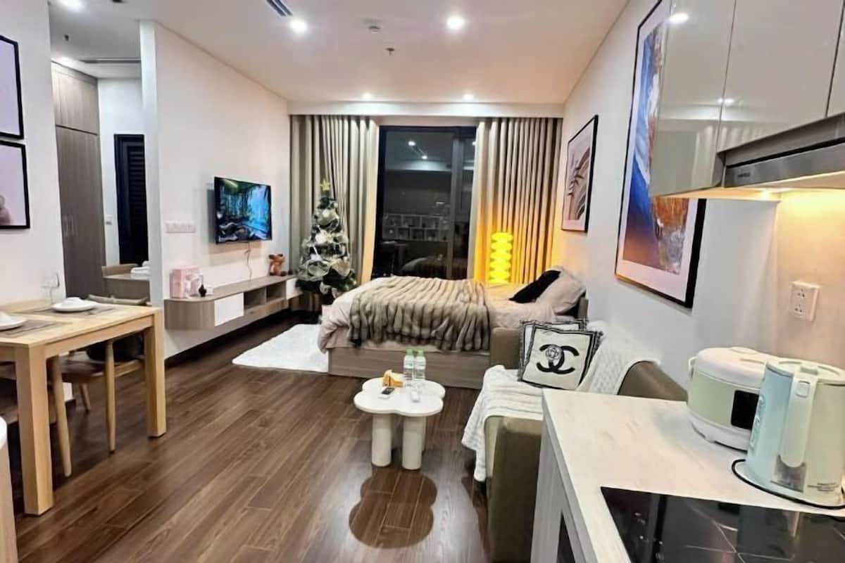 Ein modernes Hotelzimmer mit Bett, Fernseher, Essbereich und einem Weihnachtsbaum.