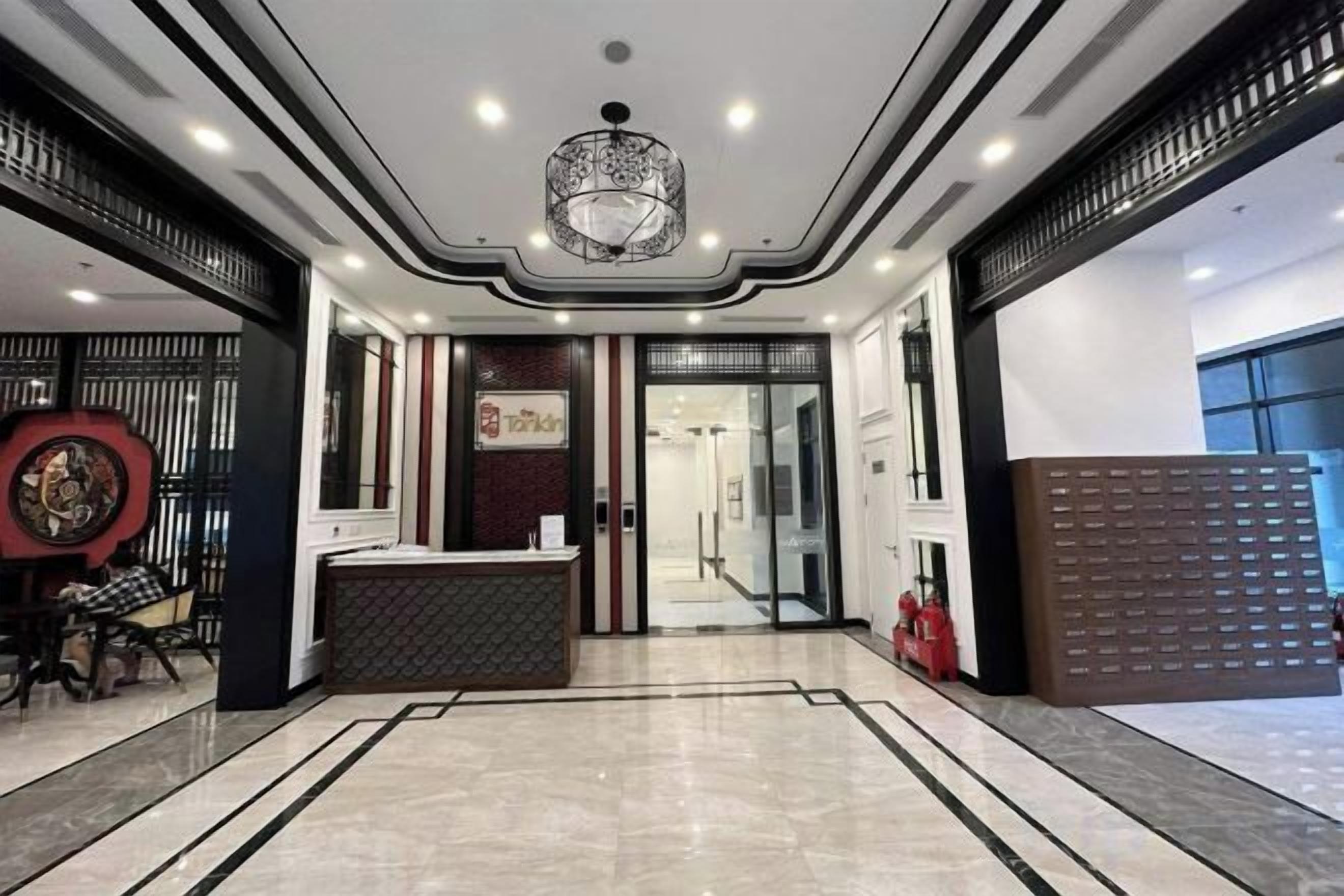 A hotel lobby with a reception desk, a chandelier, and a patterned floor.