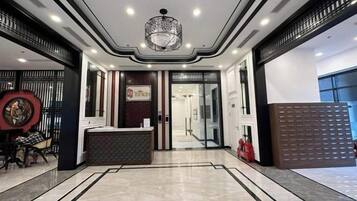A hotel lobby with a reception desk, a chandelier, and a patterned floor.
