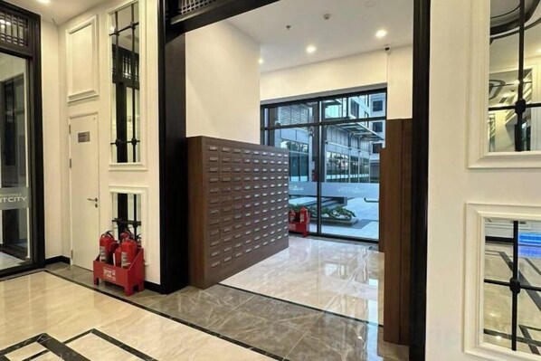 A hotel lobby with a reception desk, a fire extinguisher, and a glass door leading outside.