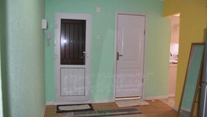 Un pasillo con dos puertas, un tapiz estampado y piso de madera.